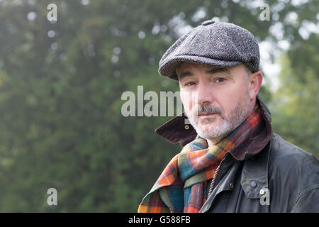 Farmer looking at the camera whilst walking in the field. Stock Photo