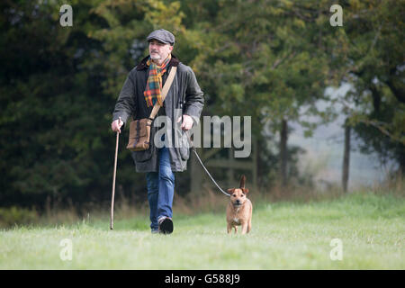 Man walking his dog in the field on a cold foggy morning. Stock Photo