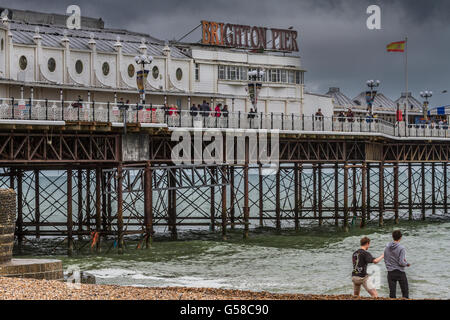 Two men on Brighton Beach in front of the  Grade11 Listed Brighton Pier  , Brighton Seafront , East Sussex , UK Stock Photo