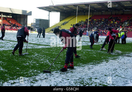 Ground staff clear snow from the pitch at Vicarage Road, before the start of the rugby union match between Saracens v Bath. Stock Photo