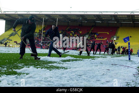 Ground staff clear snow from the pitch at Vicarage Road, before the start of the rugby union match between Saracens v Bath. Stock Photo