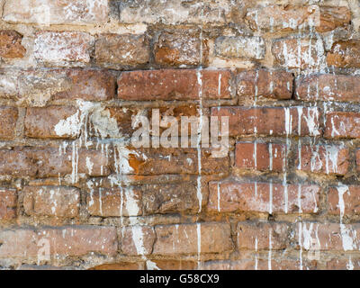 Vintage grunge uneven red brick wall with sprinkled white plaster texture background Stock Photo