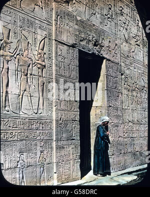 Sehr eingehend ist der Schmuck der Wände mit Hieroglyphen und figürlichen Darstellungen, was uns in ganz wundervoller Weise durch dies Bild veranschaulicht wird. Schließlich gelangen wir nach Assuan, dem einst mächtigen Syene, das mit seinen Steinbrüchen der Bezugs- und Herstellungsort all der gewaltigen Obelisken, Statuen und Denkmäler war, die die Tempel des mittleren und unteren Ögypten zieren. Von ihm hat der heute noch vielfach zu Grabdenkmälern und als Wandbelag benutzte rote Granit, der Syenit, seinen Namen. Noch jetzt sind dort zahlreiche Steinbrüche in Gebrauch.   Egypt, Edfu, Portal  Stock Photo