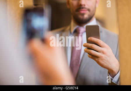 close up of man in suit taking mirror selfie Stock Photo