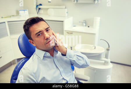 man having toothache and sitting on dental chair Stock Photo