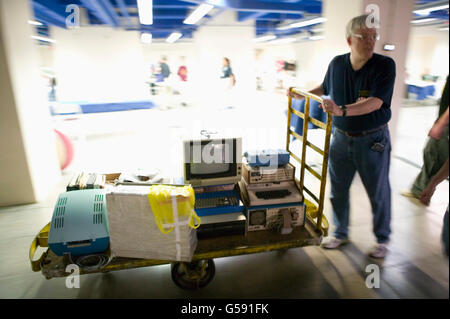 A collector and presenter at the 6th edition of HOPE, an annual hackers' convention, pushes a cart of early models of computers, Stock Photo
