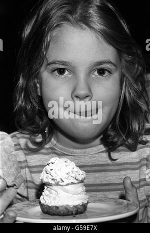 Seven year old American actress Drew Barrymore, star of the movie ET, about to eat an English teacake at the Inn on the Park, in London. Drew is the grand-daughter of silent movie star John Barrymore. Stock Photo