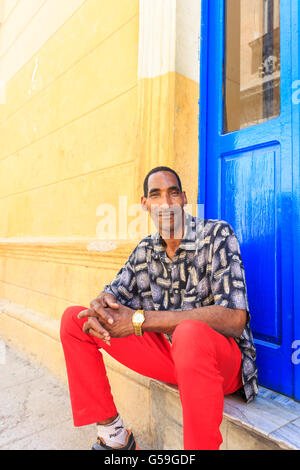 Portrait of young Cuban man sitting on the stairs of a cafe during his lunch break in La Habana Vieja, Old Havana, Cuba Stock Photo