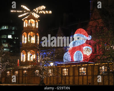 Christmas market and Big Santa Claus sitting on town hall on Albert Square at night, Manchester, England, United Kingdom