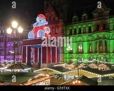 Christmas market and Big Santa Claus sitting on town hall on Albert Square at night, Manchester, England, United Kingdom