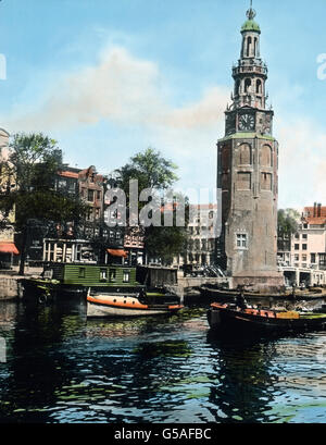 Ein bedeutender, breiter Kanal ist der Oude Schans (alte Schanze) mit malerischem Blick auf die dahinter liegenden Bauten und Türme. Dieser Kanal stellt eine Verbindung zwischen Binnen-Amstel und Ooster Dok her. Einzig schön erhebt sich an der Oude Schans der alte Montalbansturm wie ein Riese unter alten Häusern und spiegelt sich in dem klaren Wasser. Überraschend schön ist die feine Gliederung der einzelnen Stockwerke. Netherlands, 1910s, 1920s, 20th century, archive, Carl Simon, travel, history, historical, canal, water, tower, building, archjitecture, boat, waterway, city, town, inner city Stock Photo