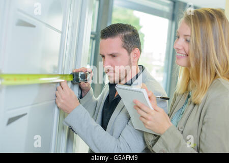man measuring a fitted cupboard