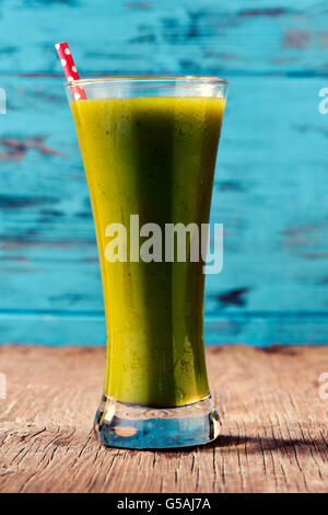 closeup of a green detox smoothie served in a glass jar with a red drinking straw patterned with white dots, on a rustic wooden Stock Photo