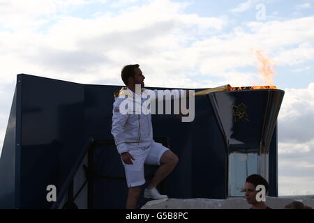 London Olympic Games - Day 1. Great Britain's Finn sailor Ben Ainslie lights the Olympic flame in Weymouth this evening Stock Photo