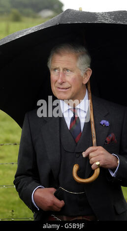 The Prince of Wales shelters from the rain under an umbrella during a visit to Sibster Farm near Wick in Scotland. Stock Photo