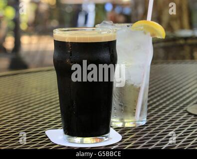 Glass of dark beer and a glass of water with lemon Stock Photo