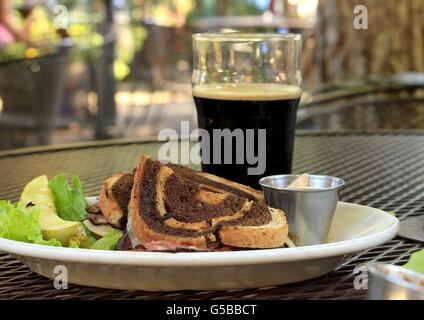 Dinner of a glass of dark beer and a Reuben sandwich Stock Photo
