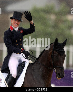 Great Britain's Kristina Cook waves whilst riding Miners Frolic in heavy rain during the Dressage stage of the Eventing at Greenwich Park, London on the second day of the London 2012 Olympics. Stock Photo