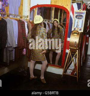 Customer Jackie Binder, in a new 'convict-style' dress designed by Pauline Fordham, looks in the mirror at Miss Fordham's boutique in Ganton Street, off Carnaby Street, London. Stock Photo