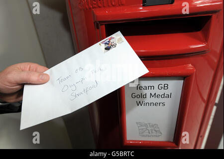 Veteran postman, Doug Mowatt, delivers a letter with a Royal Mail stamp commemorating Great Britain's Gold Medal winner to the Royal Mail office in the Olympic Park in Stratford, east London. Stock Photo