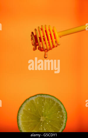 Honey flowing on lemon over yellow background Stock Photo