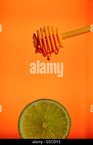 Honey flowing on lemon over yellow background Stock Photo