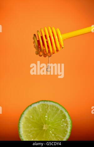 Honey flowing on lemon over yellow background Stock Photo