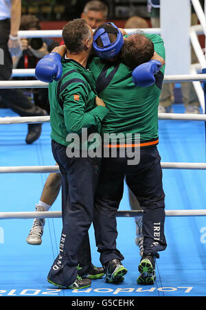 Ireland's John Joe Nevin (blue) celebrates with coaches Billy Walsh and Zaur Anita after winning his bout with with Cuba's Lazaro Alvarez Estrada in their Men's Boxing Bantam-Weight 56kg fight at the Excel Arena, London during the London 2012 Olympic Games Stock Photo