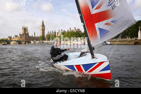 Four times Olympic sailing gold medalist Ben Ainslie sails his Finn class dinghy Rita past Big Ben, on the River Thames, London. Stock Photo