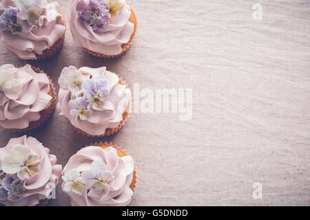 Purple cupcakes with sugared edible flowers copy space background, vintage toning Stock Photo
