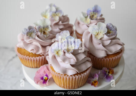 Purple cupcakes with sugared edible flowers on cake stand Stock Photo
