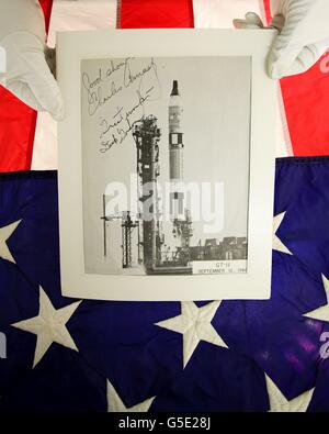 Jonathan Riley of Grand Auctions in Folkestone, Kent, holds a US flag flown for the launch of the shuttle Columbia and a photograph of the Gemini 11 lift-off in 1966, piloted by astronauts Charles 'Pete'' Conrad and Richard Gordon, which is included in an auction of space memorabilia that was collected by Nasa technician Bob Harvey, who was killed while fuelling a Titan rocket. Stock Photo