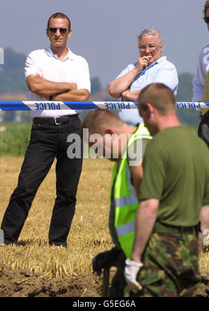 Joseph (L) son of Elizabeth Bowden (C), who is the sister of Flying Officer Ted Kosh, a second world war RAF pilot who was killed when he crashed his plane into a field Near Winchelsea, Sussex in July 1944, watches as RAF personel dig trying to find his remains. * The remains of the wartime RAF fighter pilot are being exhumed in East Sussex as part of an investigation into claims that grave-robbers had raided the site where he crashed. Stock Photo