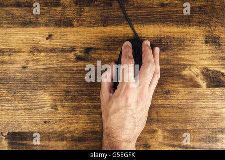 Man using computer mouse, top view of male hand and pointing device on office desk Stock Photo