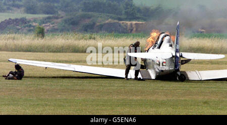 A two seater Harvard T6 plane Crashes as it takes off at RAF Duxford, Cambridgeshire, prior to an air show. The Pilot lies on the ground as his Passenger goes back to the plane as it catches fire although It is not thought that anyone was injured. * in the accident at the Imperial War Museum's aviation headquarters at Duxford. Stock Photo