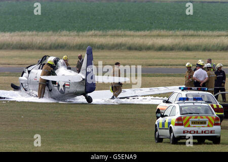 Fire crews examine a two seater Harvard T6 plane which Crashed as it takes off at RAF Duxford, Cambridgeshire, prior to an air show. It is not thought that anyone was injured in the accident. * at the Imperial War Museum's aviation headquarters at Duxford. Stock Photo