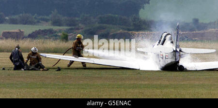 Fire crews attend to the crew and extinguish the fire after a two seater Harvard T6 plane Crashed on take off at RAF Duxford, Cambridgeshire, prior an air show. It is not thought that anyone was injured in the accident at the Imperial War Museum's aviation headquarters at Duxford. See PA story AIR Crash. PA Photo: Andrew Parsons. Stock Photo