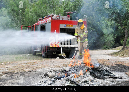 Fireman in protective clothing extinguishes a fire as part of a fire fighting drill Stock Photo