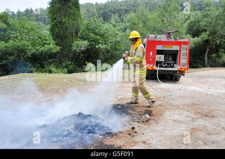 Fireman in protective clothing extinguishes a fire as part of a fire fighting drill Stock Photo