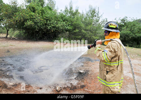 Fireman in protective clothing extinguishes a fire as part of a fire fighting drill Stock Photo