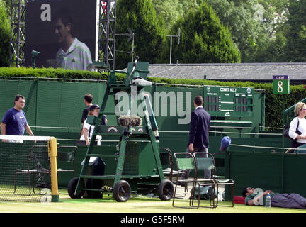 NO COMMERCIAL USE: A groundsman sleeps as a big screen shows Great Britain's Tim Henman in action against Goran Ivanisevic of Croatia during their Mens Semi Final match at the 2001 Lawn Tennis Championships at Wimbledon, London. Stock Photo