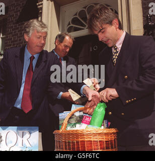 Devon MP John Burnett (L) and Adam Southwell (R), acting chairman of the Dartmoor Tourist Association bring local produce for Prime Minister Tony Blair to Downing Street . * They are highlighting that the Dartmoor National Park is due to reopen this coming weekend, and hope to encourage Mr Blair and Tourism Minister Kim Howells (centre) to visit the area this summer. Recent forecasts have estimated that in the aftermath of the foot and mouth crisis Devon may lose 357 million in tourism revenue and 11,000 jobs. Stock Photo