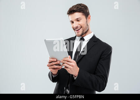 Cheerful young businessman using tablet and laughing over white background Stock Photo