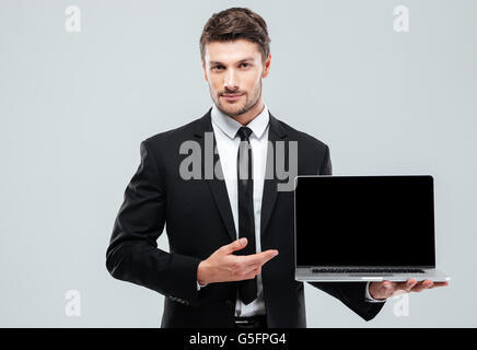 Handsome young businessman showing blank screen laptop over white background Stock Photo