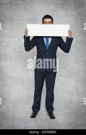 businessman hiding behind a sheet of paper Stock Photo