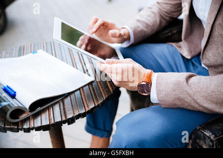 Closeup of man sitting and using tablet in outdoor cafe Stock Photo