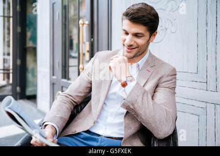 Smiling man reading newspaper outdoor in cafe Stock Photo