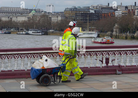 Two workmen in high visibility clothing and hard hats crossing a bridge over the river Thames in London, faces obscured Stock Photo