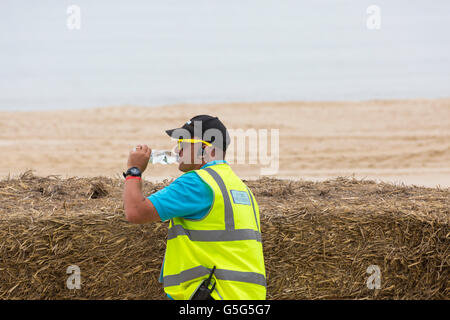 Marshall wearing hi vis vest and drinking bottle of water at Bournemouth Wheels Festival in June Stock Photo