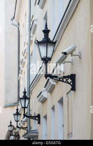 Antique lanterns and modern surveillance cameras on building facade, diminishing perspective Stock Photo